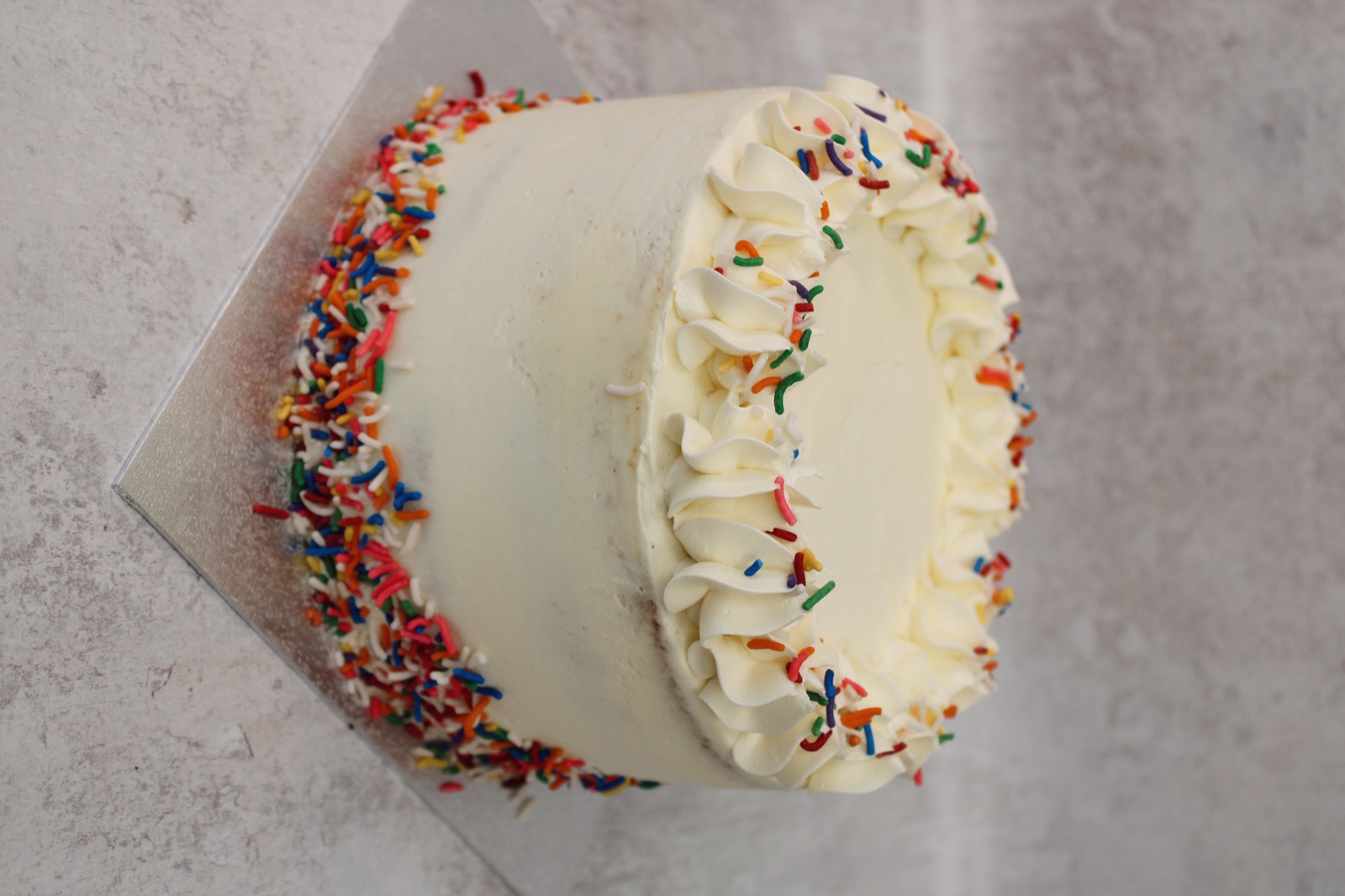 Round celebration cake with colourful sprinkles, overhead view