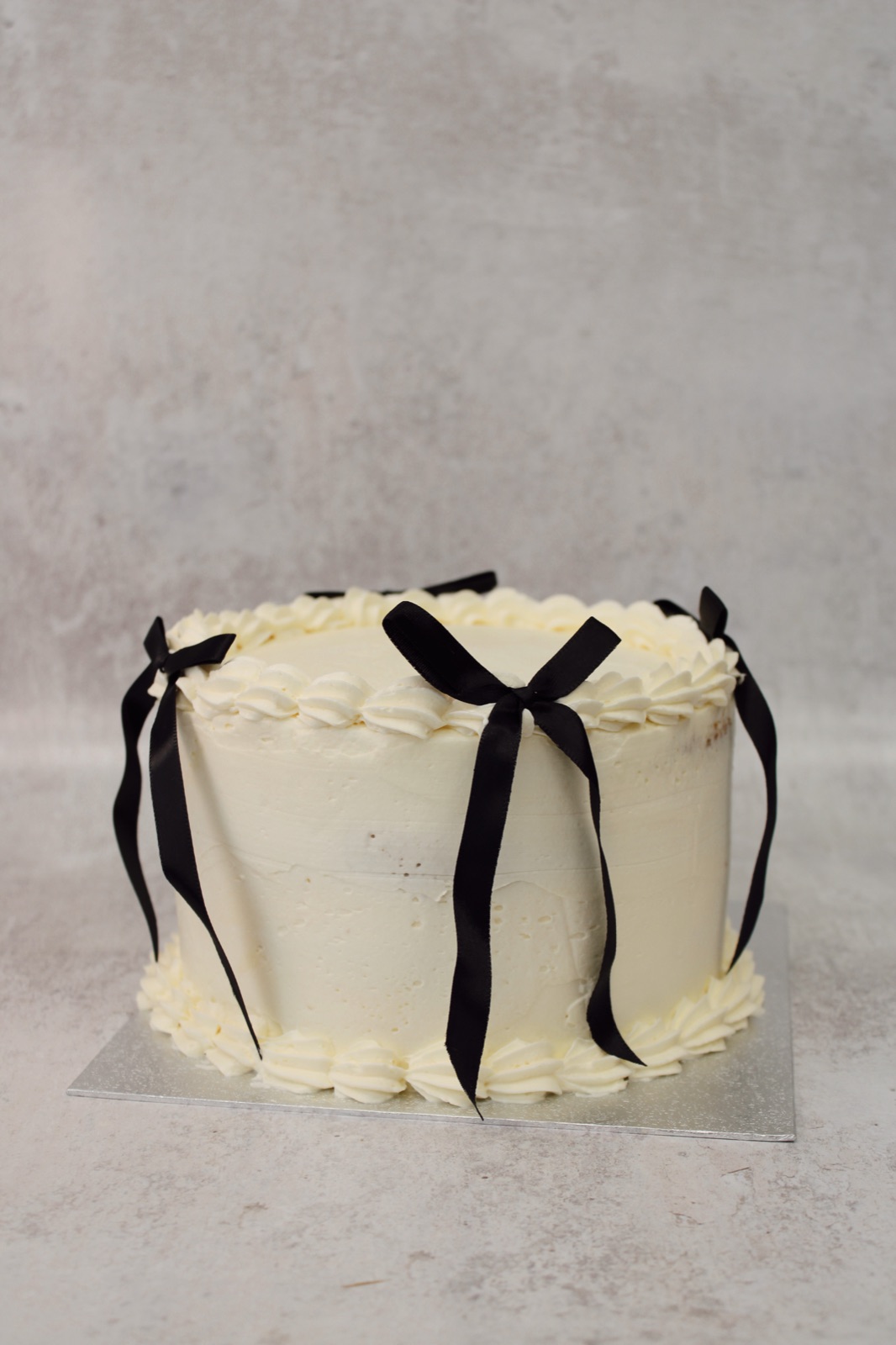 Elegant cream celebration cake with black ribbon bows